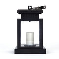 Solar LED candle light with black plastic shade, monocrystalline panel, and warm white illumination on garden path