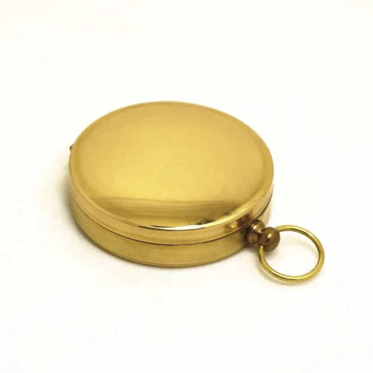 Gold metal flip compass with open lid showing compass face, pocket watch style