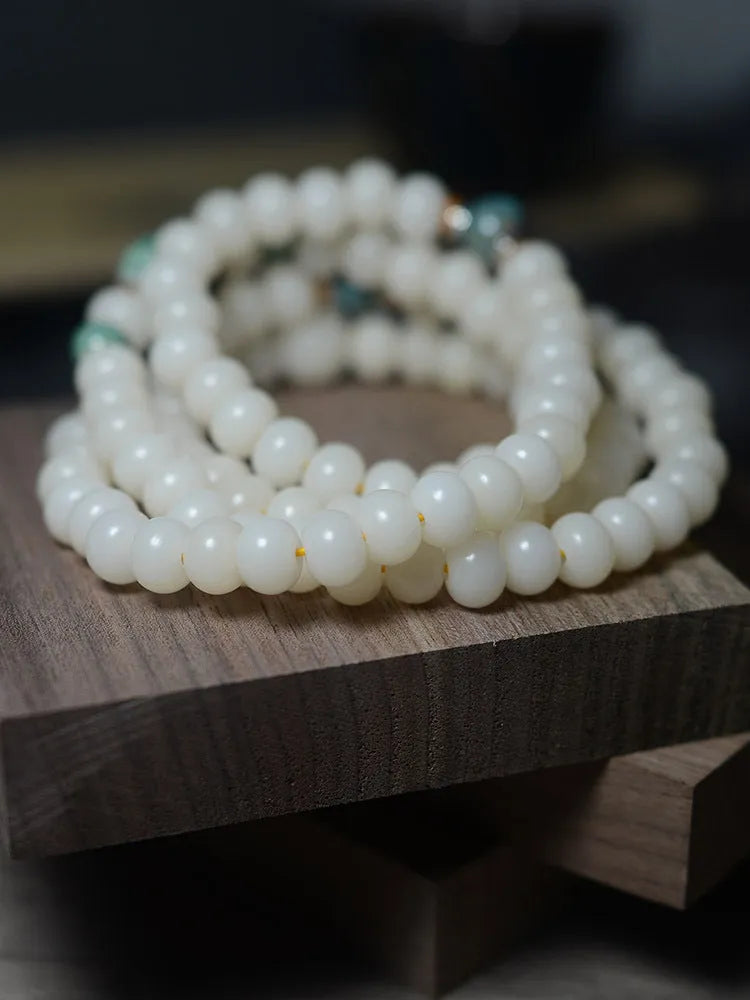 White jade bodhi root bracelet with 108 flat round beads in two sizes on wrist