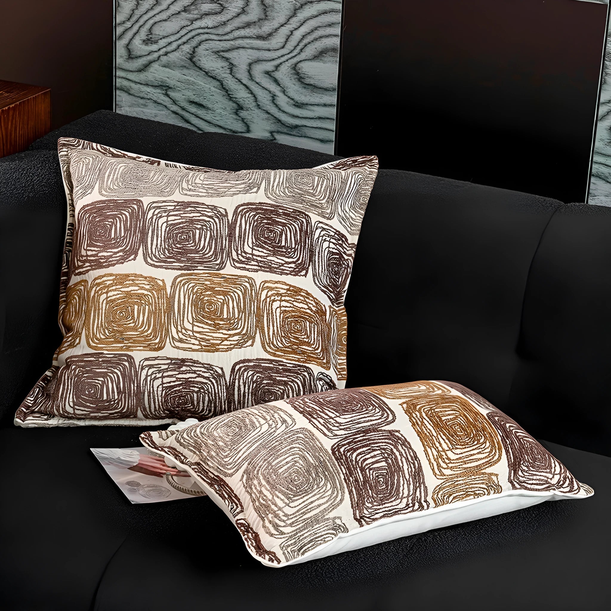 Square cream and coffee abstract coil pattern cushion cover on a grey sofa