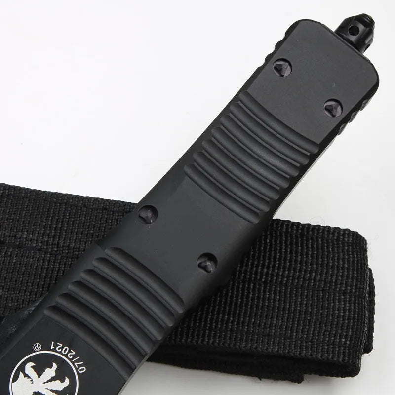 Black folding knife with D2 steel blade and aviation aluminium handle open on a dark surface
