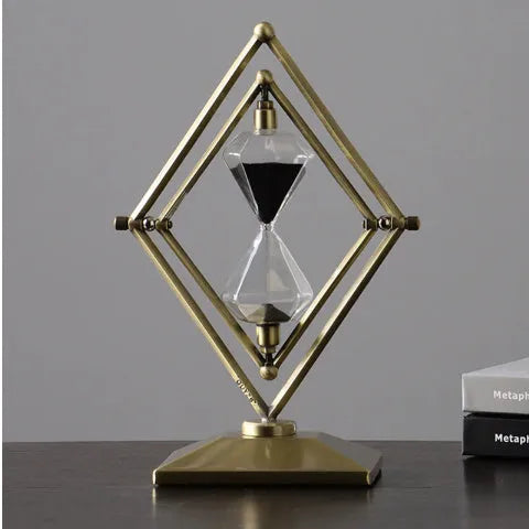 Glass sand clock timer with detailed metal ornaments in a bronze finish, showing modern simplicity style.