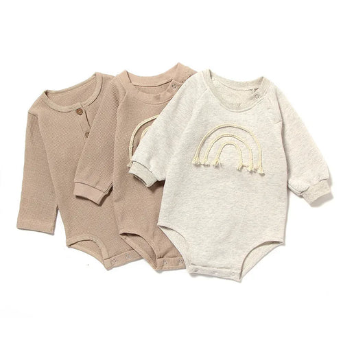 Long-sleeved waffle cotton baby romper in a neutral colour on a hanger, showing the triangular climbing front closure.