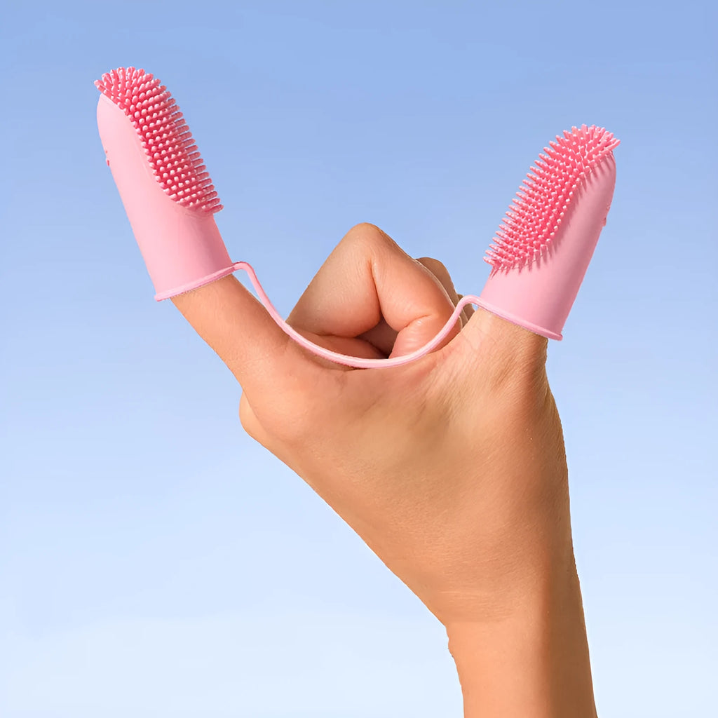 Close-up of blue green and pink silicone finger sleeves for pet dental cleaning on a hand.