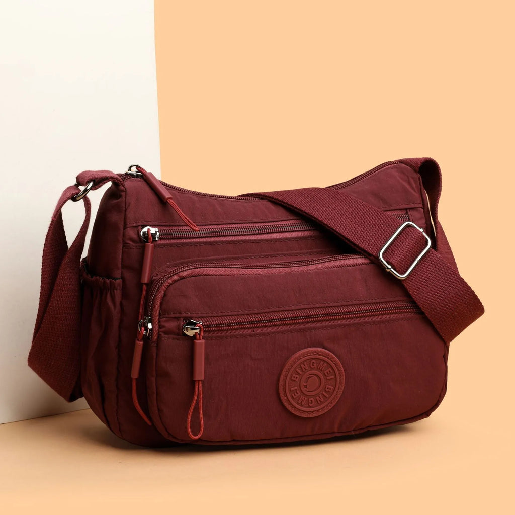Grey water-repellent nylon crossbody bag showing outer pocket and internal organiser compartments.