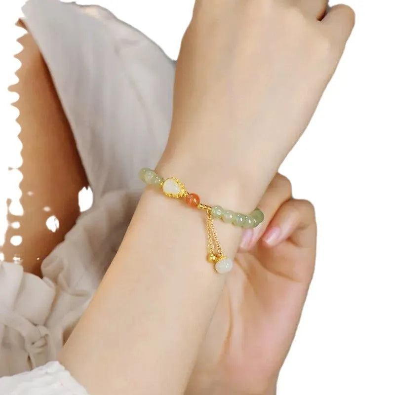Women's jade bracelet with gold-plated gourd charm and Fu character pendant on a 6mm bead.