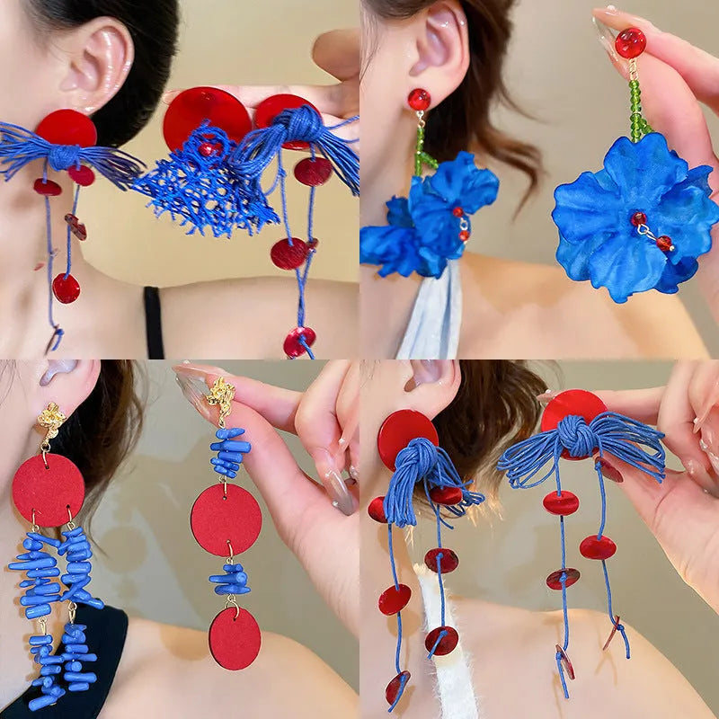 Handmade geometric cloth earrings with a blue resin flower and silver detail on a white background.