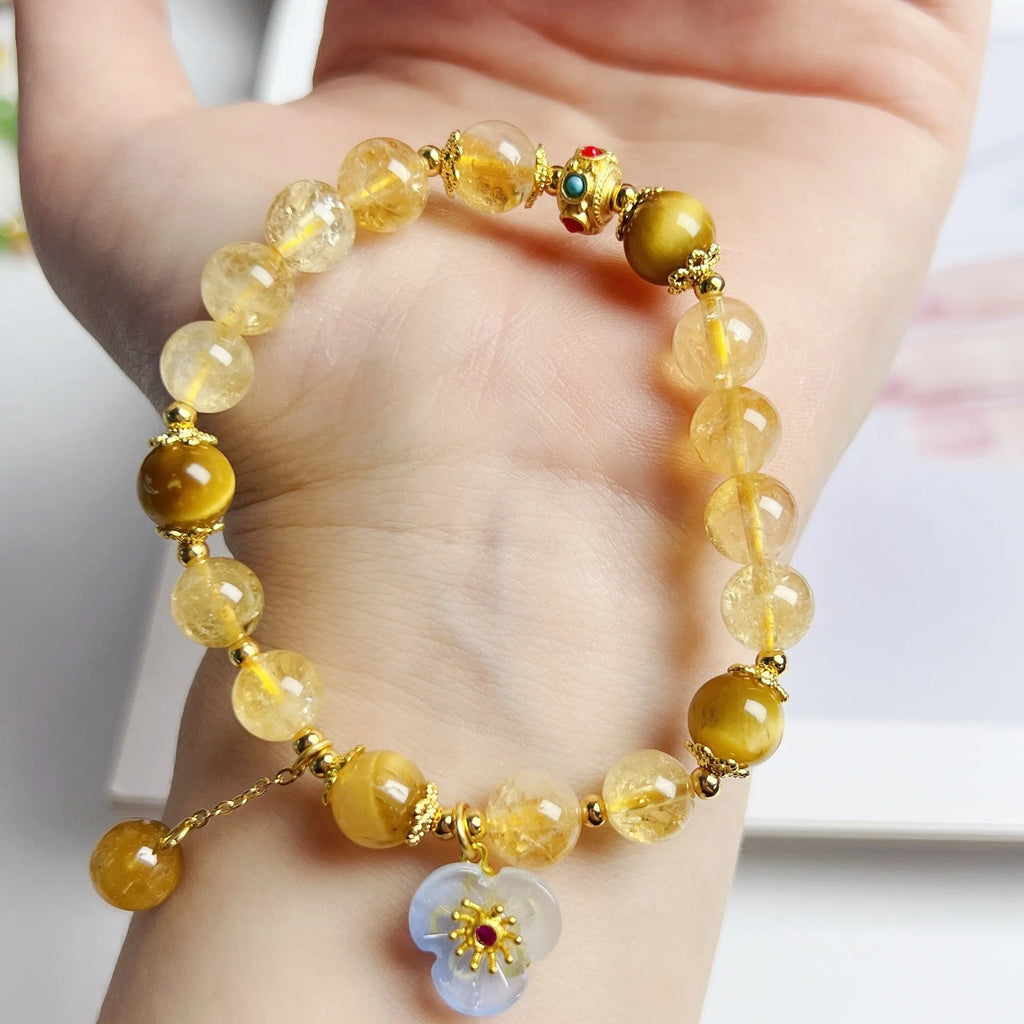 Women's citrine crystal bracelet with gold-plated flower tassel design on wrist.