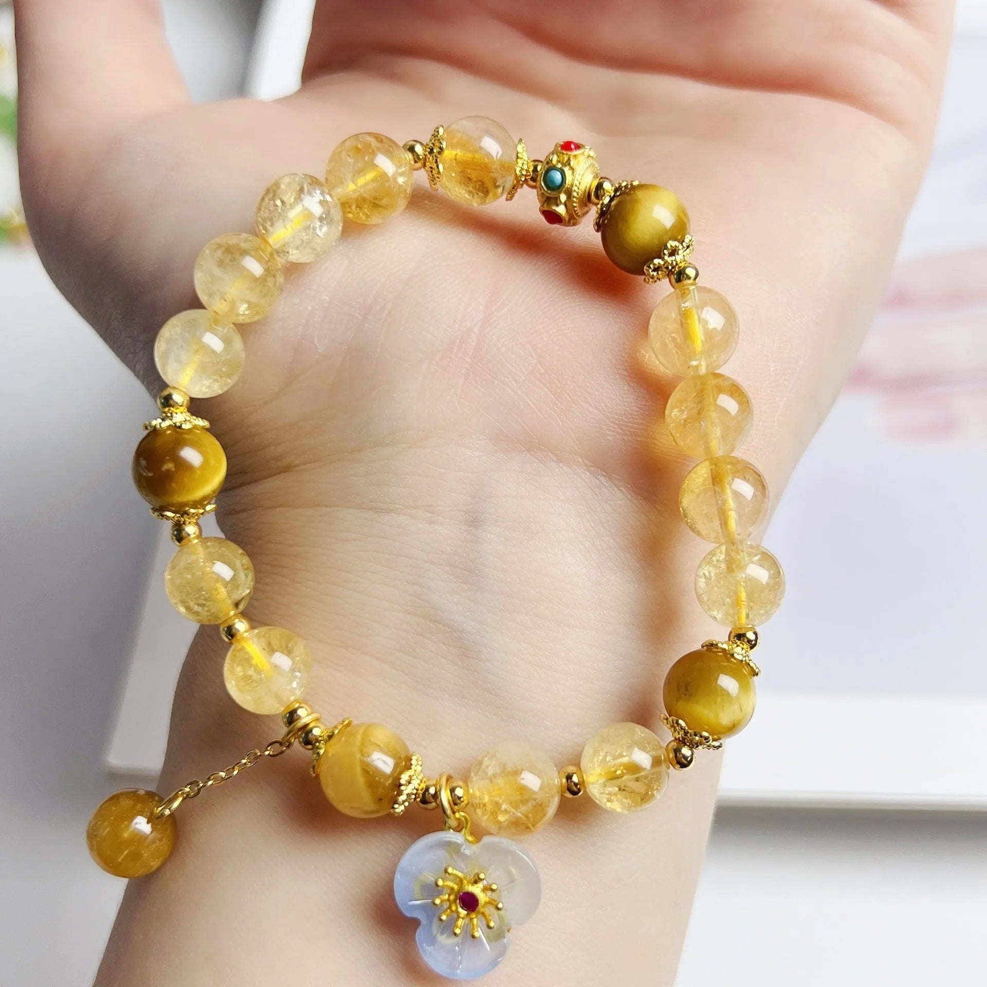 Women's citrine crystal bracelet with gold-plated flower tassel design on wrist.