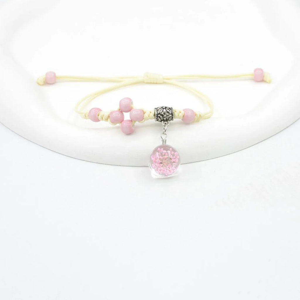 Close-up of a hand-woven glass bracelet with large 1.4cm beads containing real dried flowers in various colours.