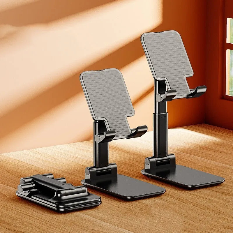 White folding telescopic mobile phone bracket holding a smartphone on a desktop.