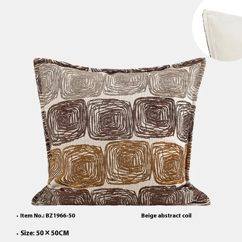 Square cream and coffee abstract coil pattern cushion cover on a grey sofa