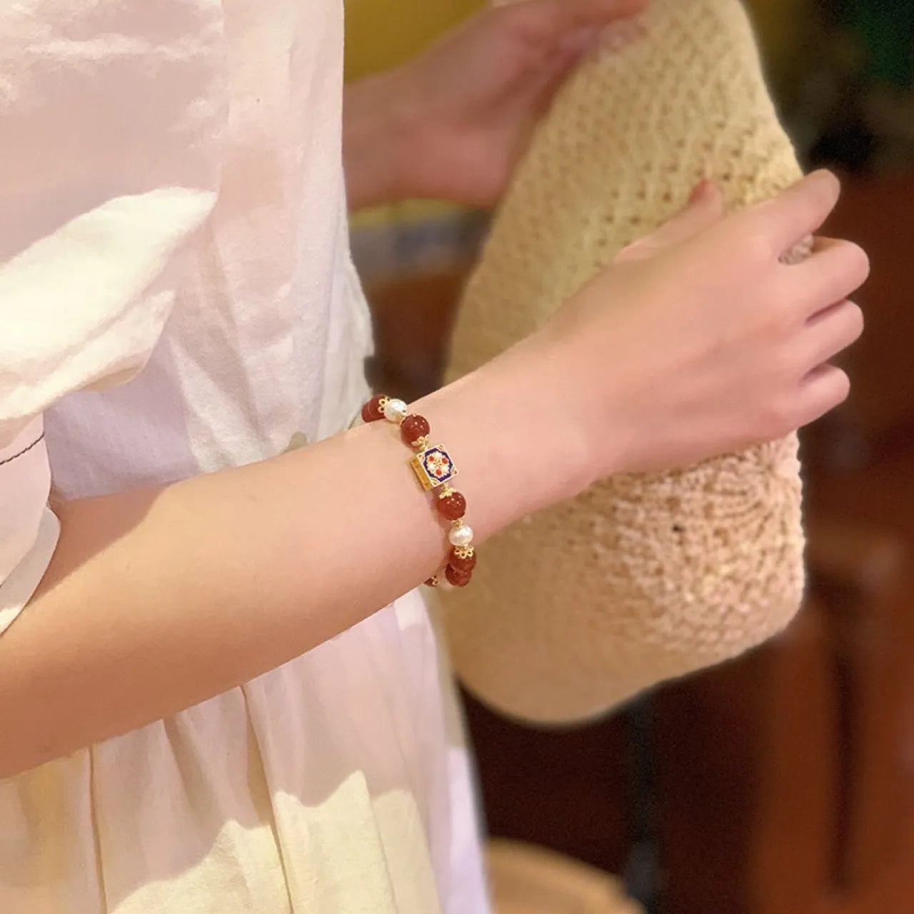 Red agate and pearl women's bracelet with constellation design on a wrist.