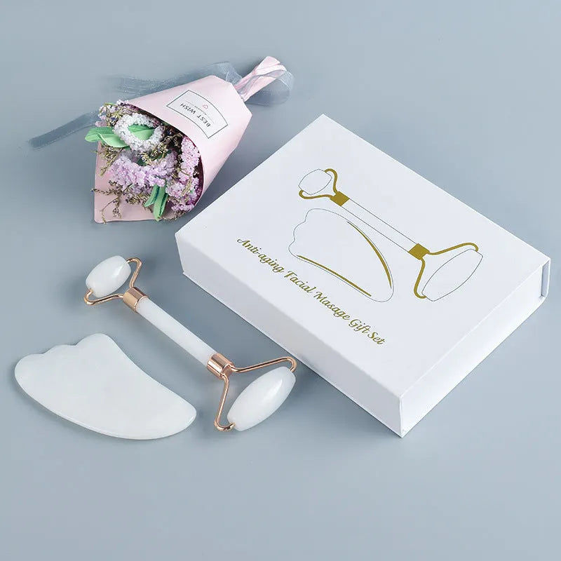 White jade facial roller and gua sha tool set with rose quartz board on a neutral background.