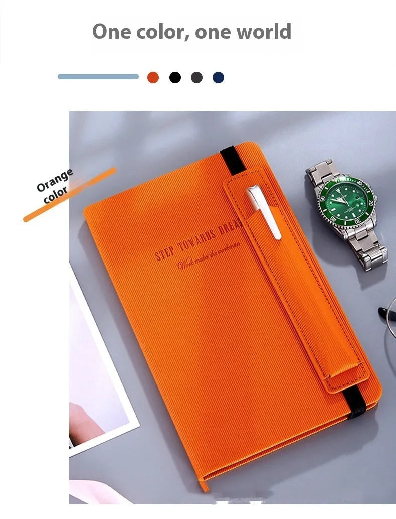 A5 faux leather notebook with pen insert and strap, open on a desk showing lined pages