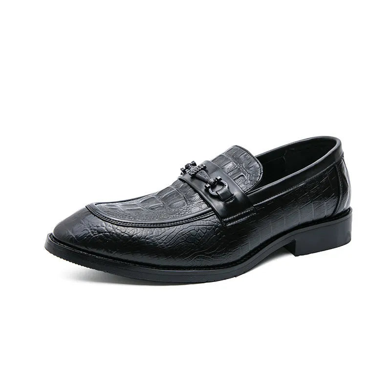 Men's black slip-on formal shoes with pointed toe and belt buckle detail on a light background