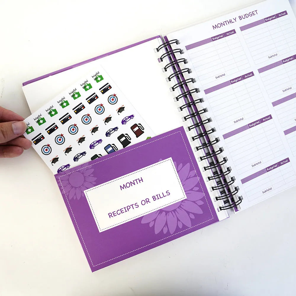 J12 purple coil-bound financial planning notebook with budget stickers and paper clips on Daolin paper pages