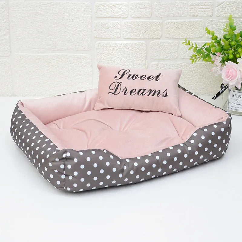 Polka dot square dog bed with matching embroidered pillow in grey, shown in a home setting.