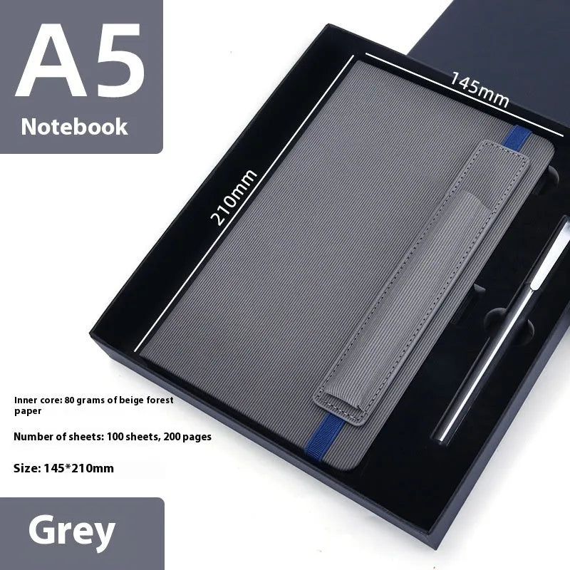 A5 faux leather notebook with pen insert and strap, open on a desk showing lined pages