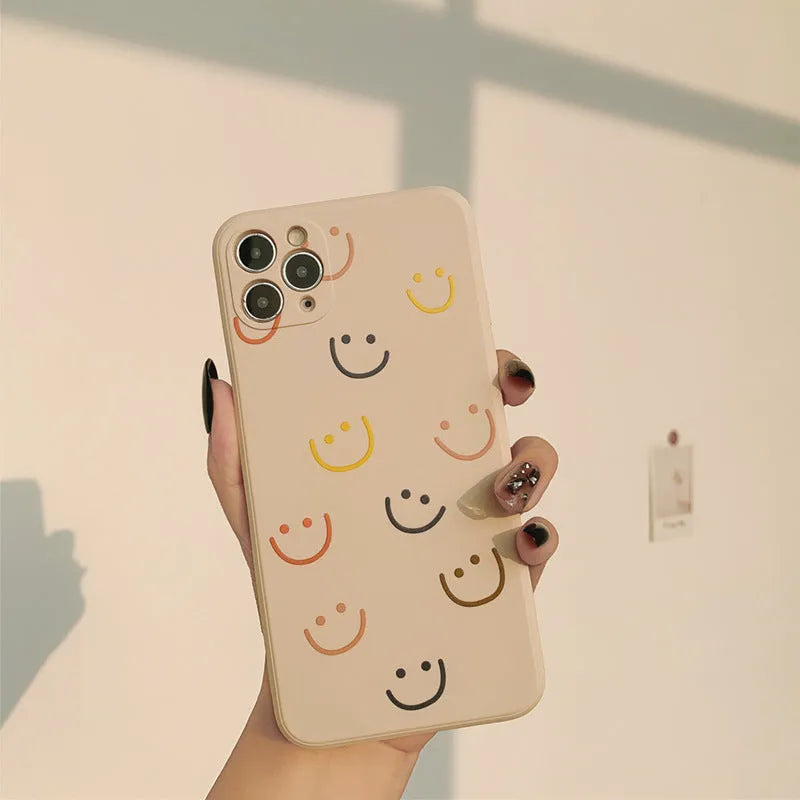 Simple TPU silicone iPhone case with painted smiley face and graffiti design on a table