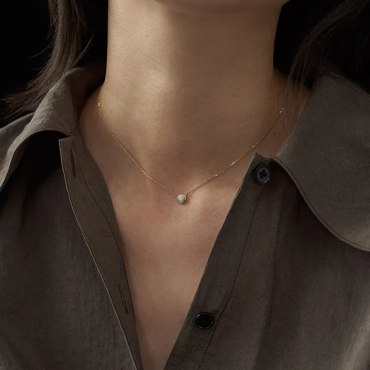 Simple geometric oval pendant necklace in gold plating on a silver chain.