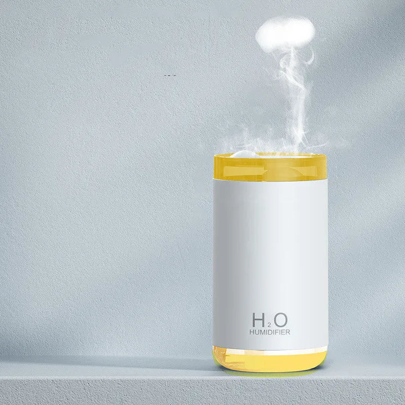 White USB humidifier emitting jellyfish-shaped smoke ring mist with warm night light glow on a desk.