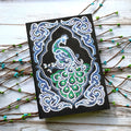 A5 black notebook with a peacock diamond painting design and packets of shaped and bright drill rhinestones.