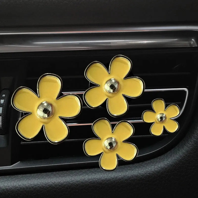 Set of four metal flower-shaped car vent aromatherapy clips in assorted colours