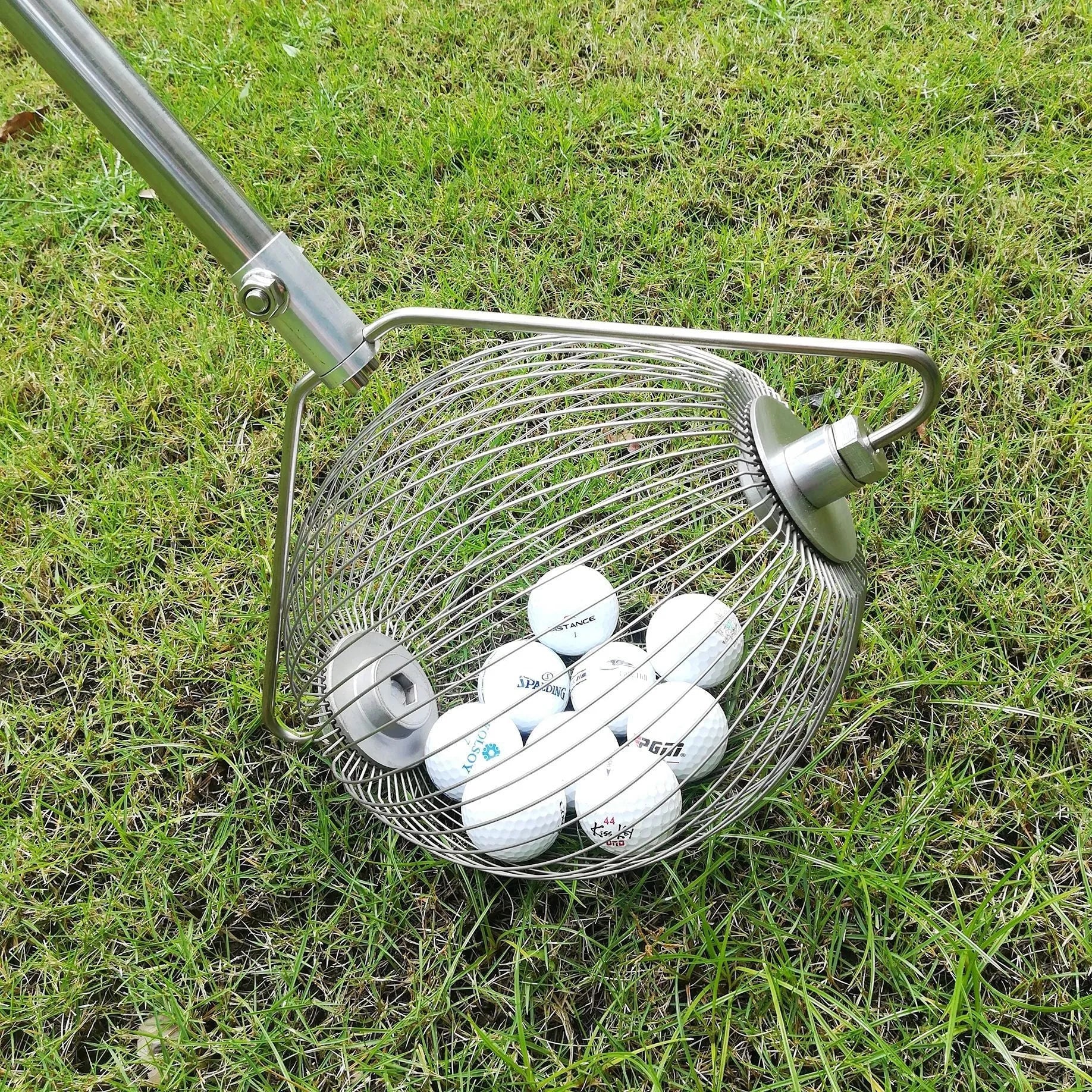 Metallic stainless steel golf ball picker on green grass