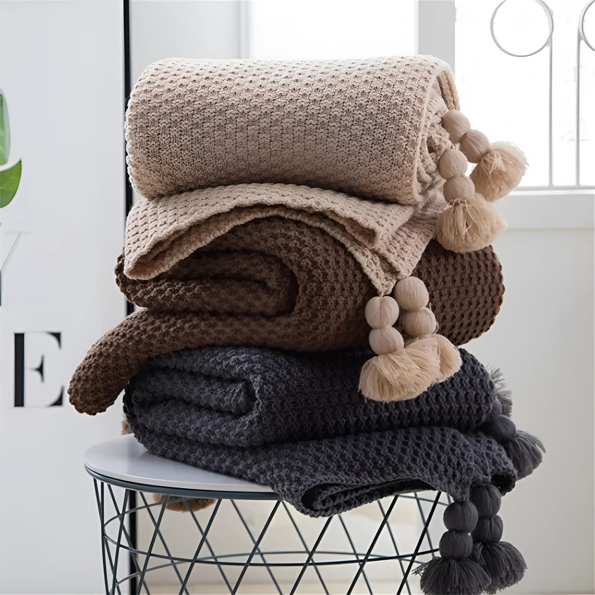 Acrylic knitted fringed blanket in beige colour on a sofa, showing texture and size.