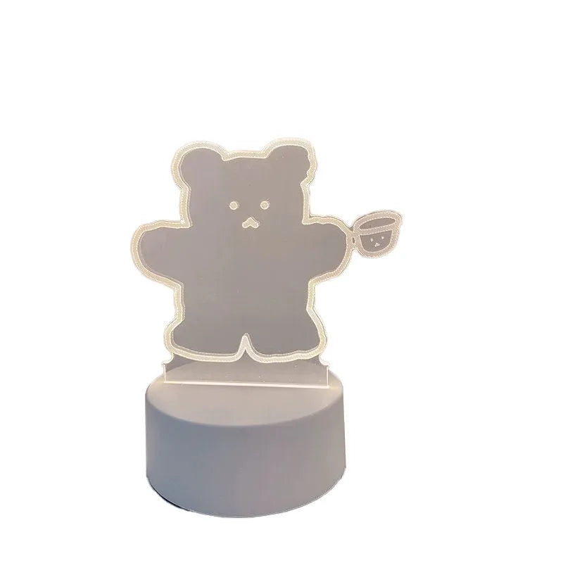 Teddy bear cartoon LED night light with acrylic shade on a table, USB cable attached