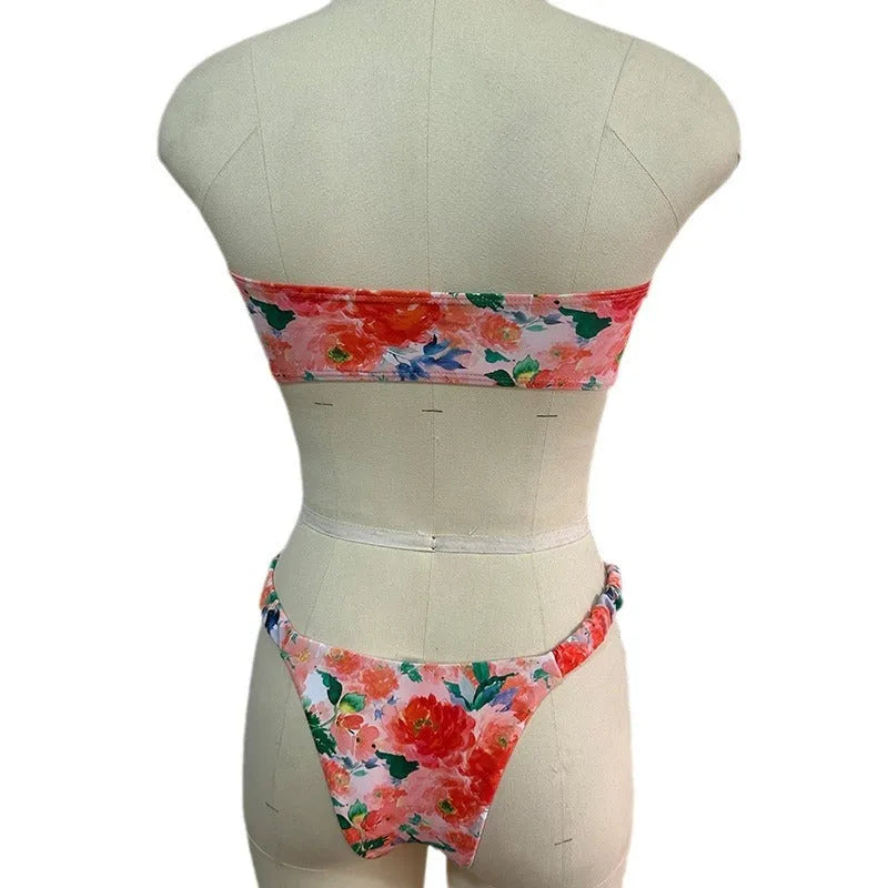 Women's floral print tube top bikini set with lace detailing on a blue background.
