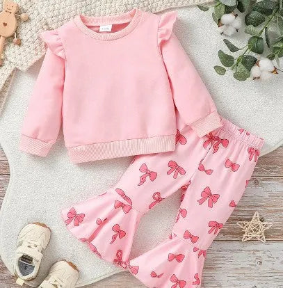 Pink two-piece girls' suit with long sleeve flounced sleeve knitted sweater, printed bow, and flared pants on white background