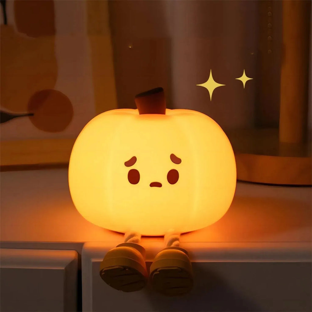 Soft orange pumpkin-shaped silicone night light with a warm glow, showing its compact size on a table.