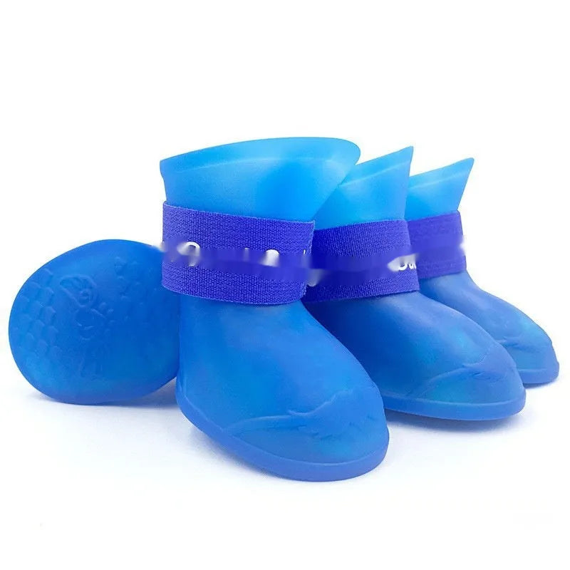 Set of four soft-soled rubber pet rain shoes in assorted colours on a grey background.
