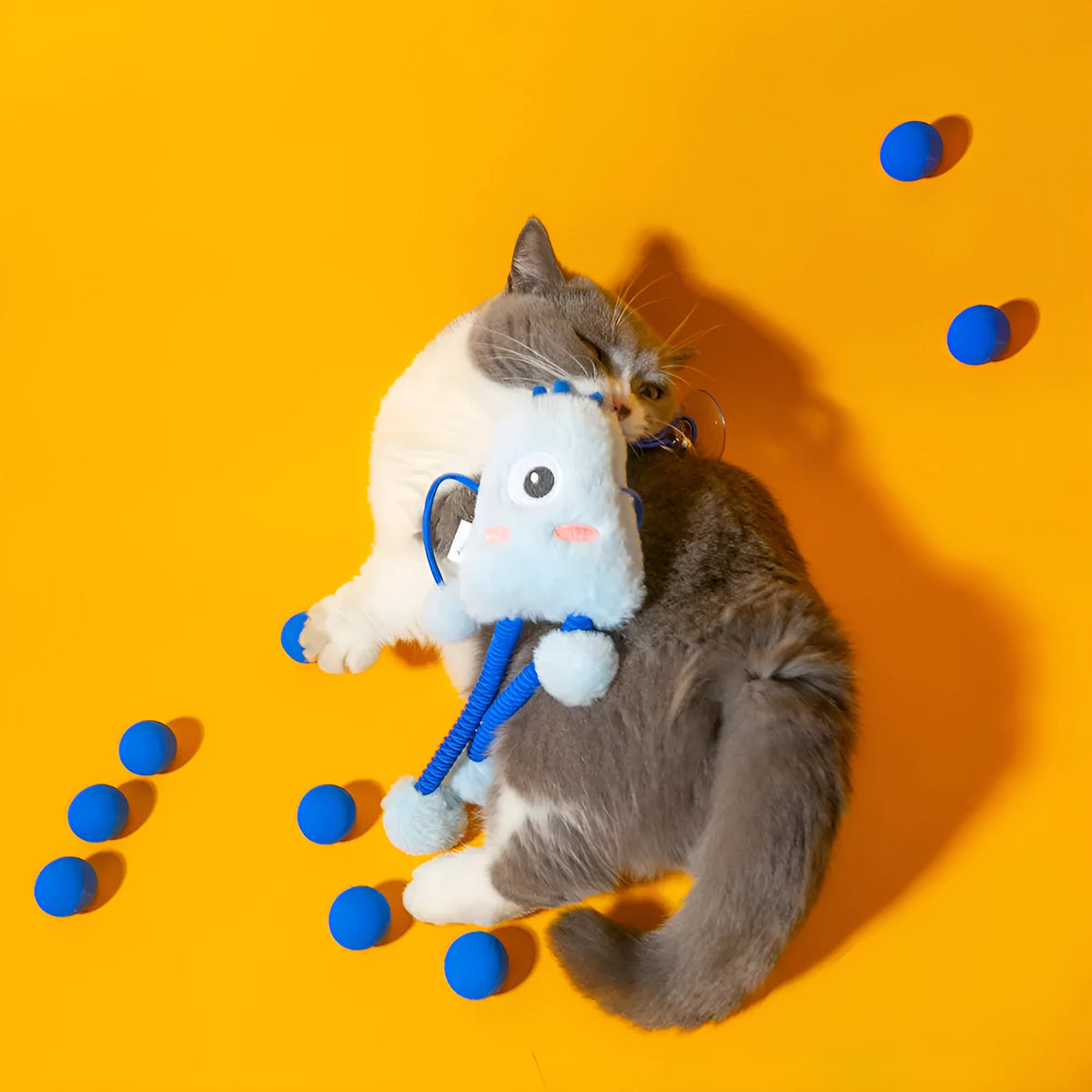 Blue plush elastic cat toy with bell in a ring shape on a light background