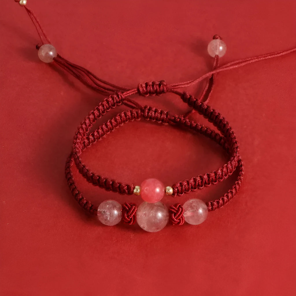 Woven red rope bracelet with a spherical strawberry quartz bead and alloy clasp.