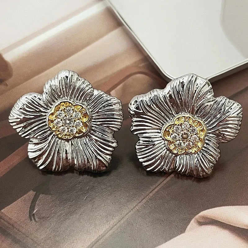 Close-up of women's copper stud earrings with a textured floral design in a two-tone colour.
