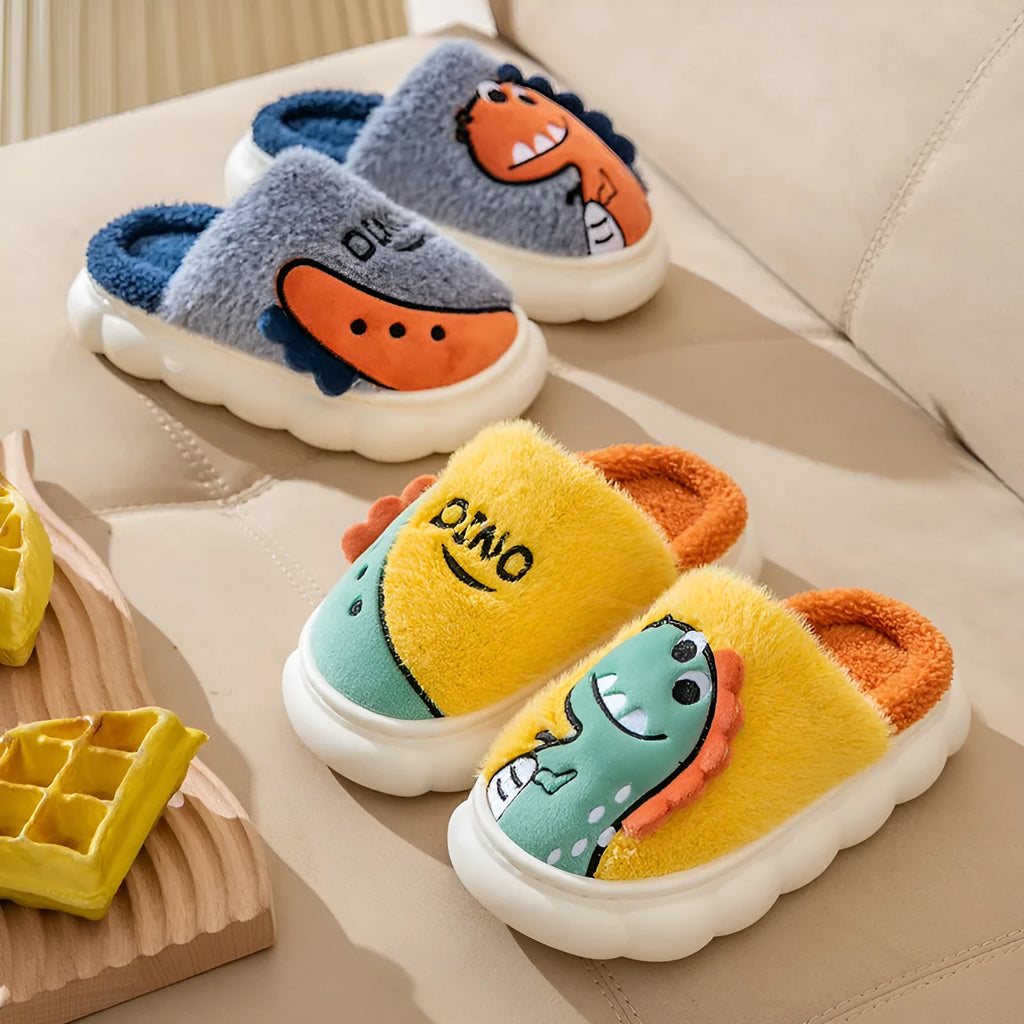 A pair of plush grey dinosaur-themed couple slippers with a thick sole, shown next to coffee and orange colour variants.