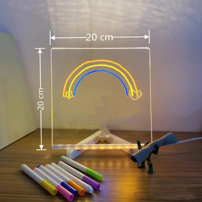 DIY acrylic LED message board lamp on a desk with colourful writing, showing USB cable and pens.