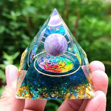 Clear epoxy resin pyramid ornament with natural crystal gravel inside on a wooden surface.