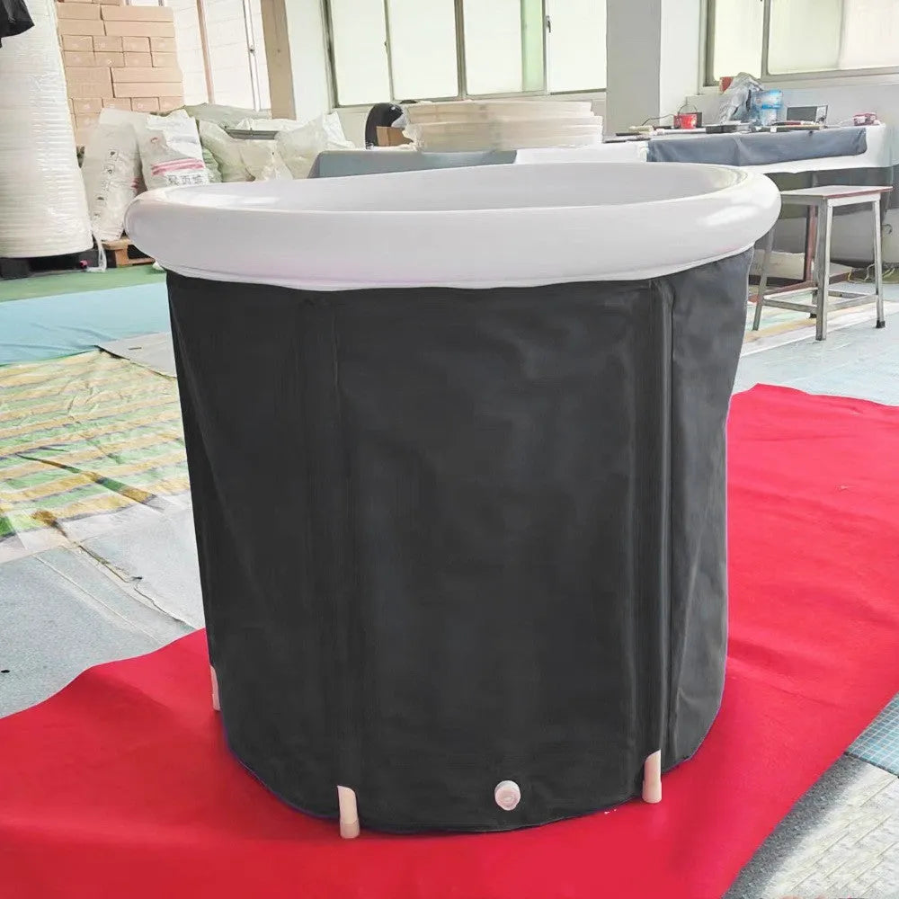 Black inflatable portable ice bath tub with weather lid, shown outdoors.
