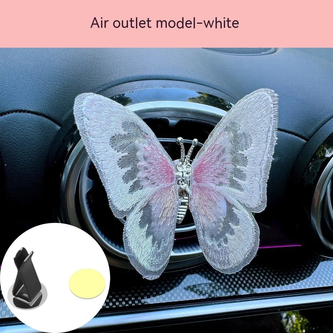 Fabric embroidered butterfly car air vent decoration in multiple colour options on a dashboard.