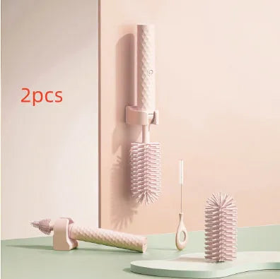 Pink and green electric baby bottle cleaning brush with rotating silicone head on a table