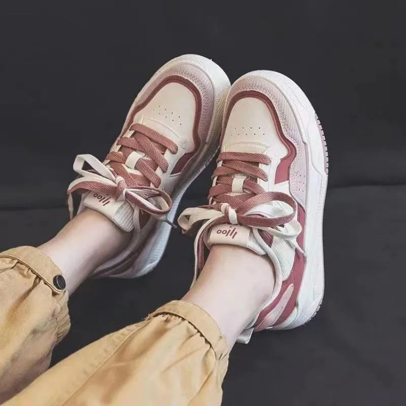 Women's pink and white low-top sneakers with a height-increasing rubber sole on a neutral background.
