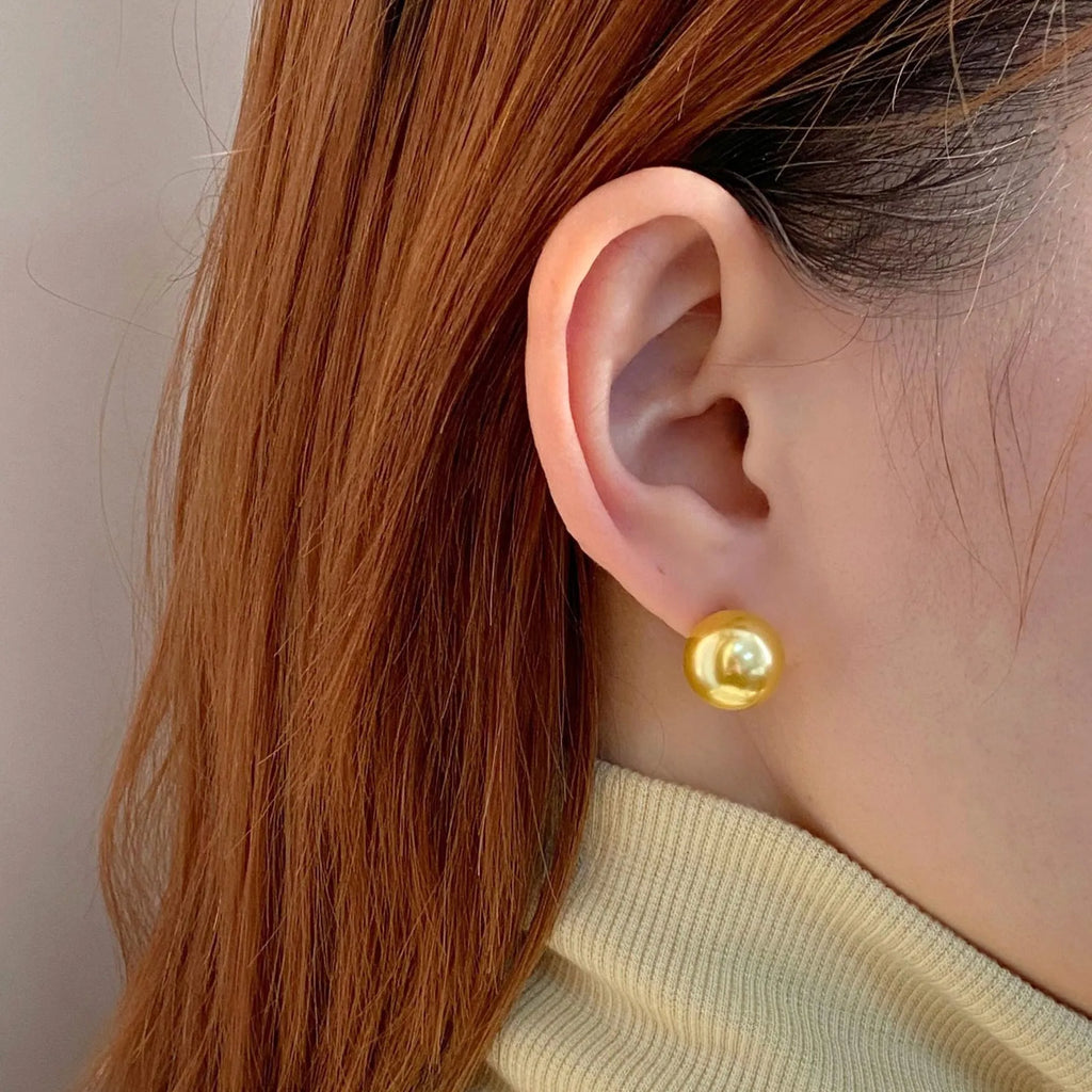 A pair of large pearl stud earrings with a geometric silver setting and an eight-point star detail.