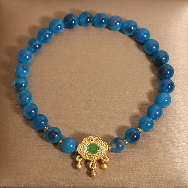Blue sugar heart agate safety lock pendant on a women's crystal bracelet with rhinestone details.