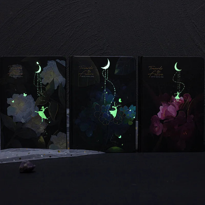 A5 notebook with luminous cover open to show colourful illustration pages, in Deep Blue, Gold, Light Blue, and Purple colour options.