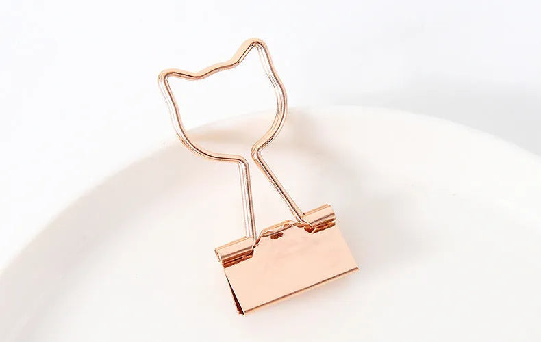 Small gold-plated metal office clip with a long tail, shown in a choice of flamingo, love, clouds, cat, and cactus shapes.