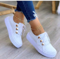 Women's white lace-up flats sneakers with round toe and silver rivet details on the low upper.